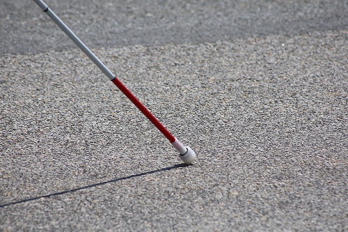 A white cane is held with the tip against pavement Source: MorgueFile